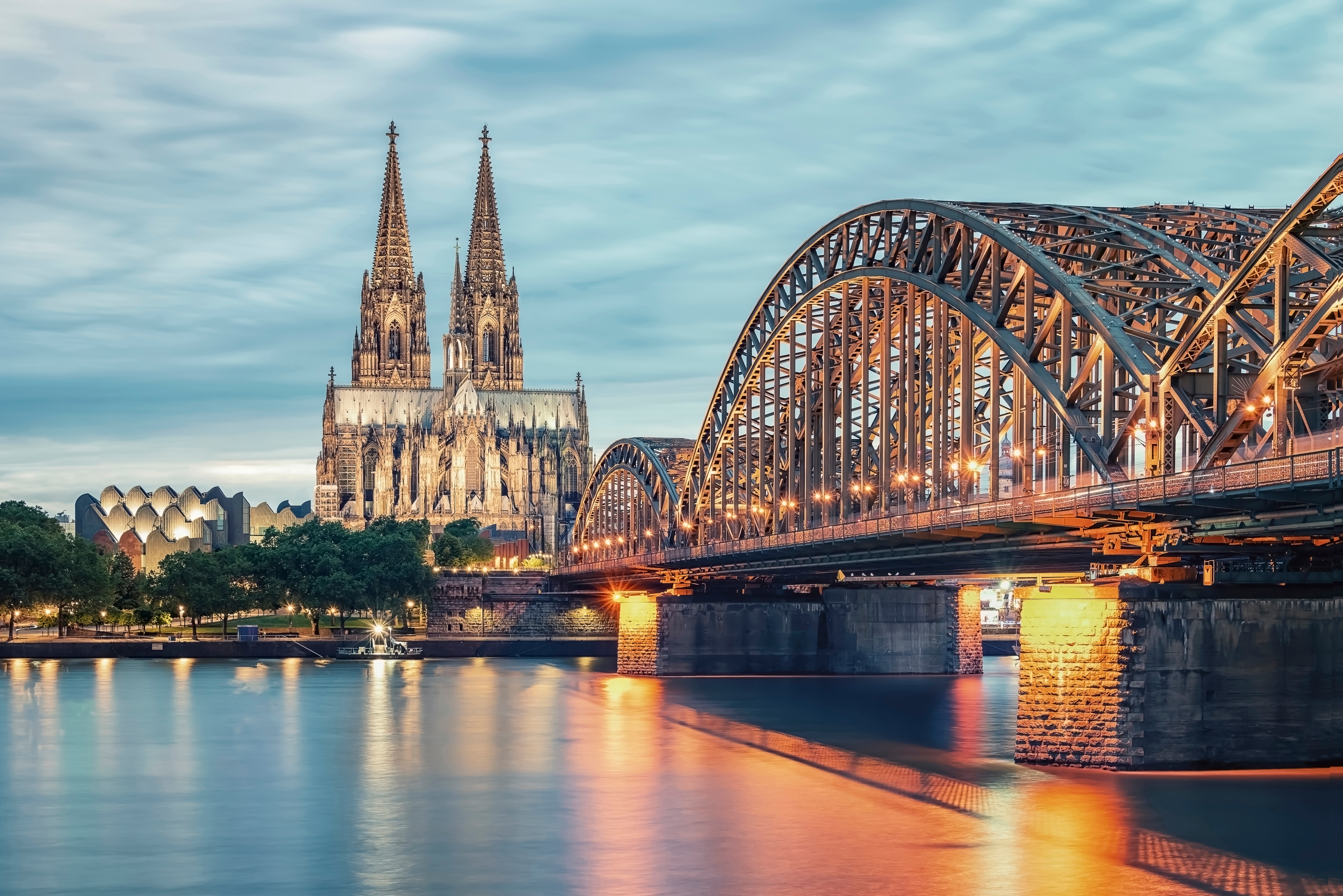 Blick auf den Kölner Dom und die Hohenzollernbrücke über dem Rhein bei Dämmerung