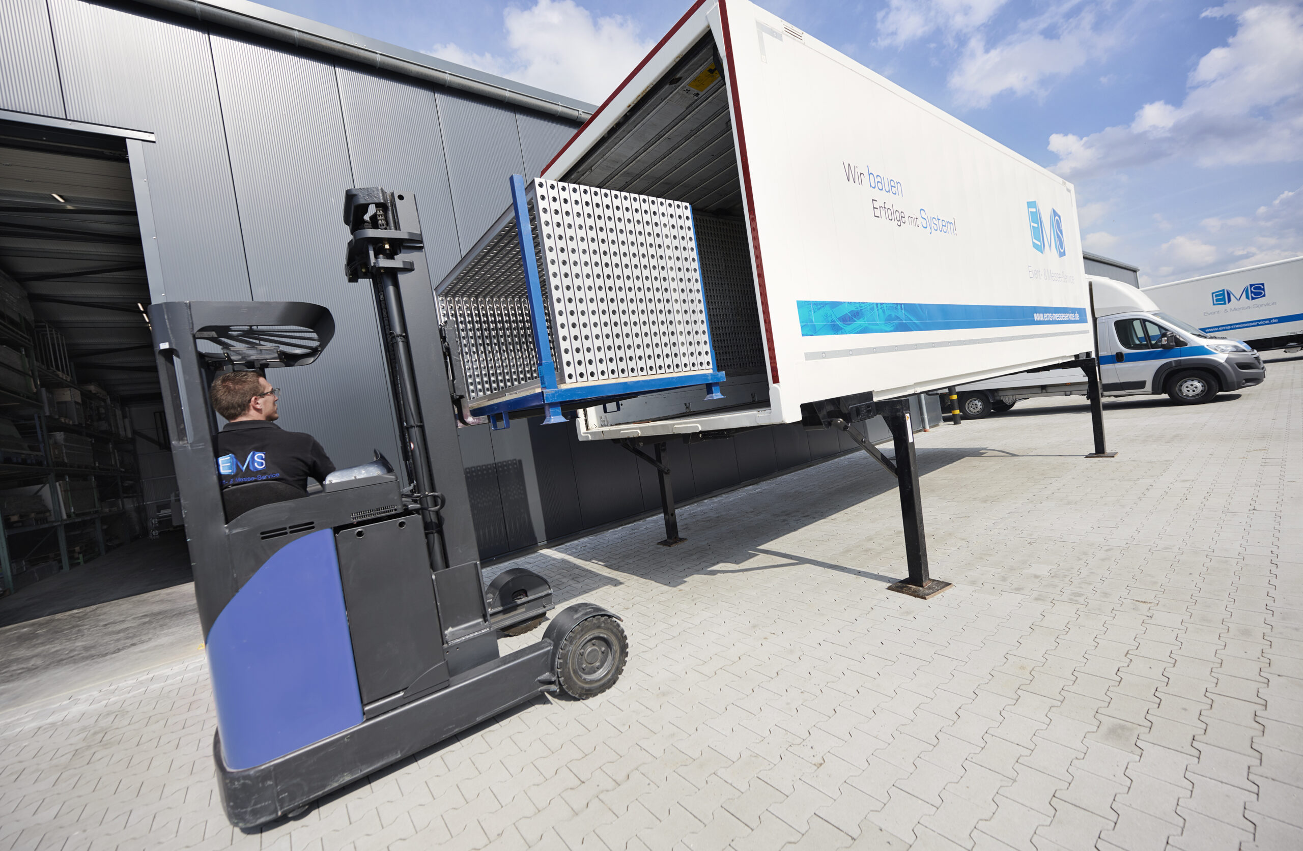 Mitarbeiter von EMS lädt Elemente eines Messestands in einen Container für den Transport zur Messe