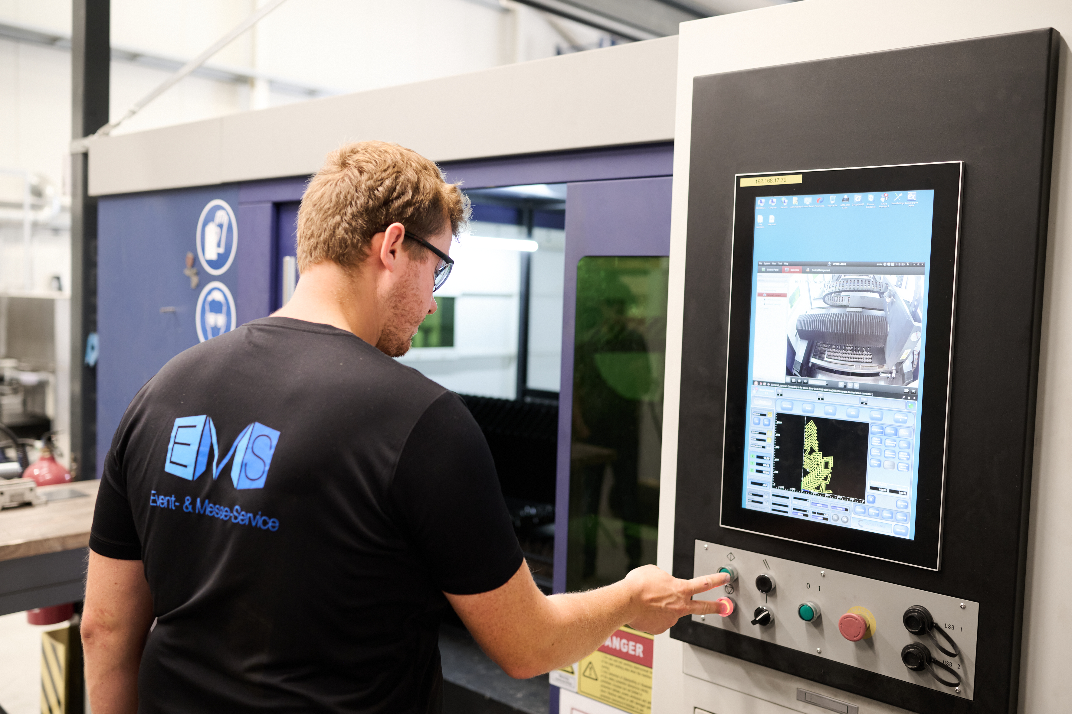 EMS Mitarbeiter arbeitet in der Produktionshalle an einem Messestand